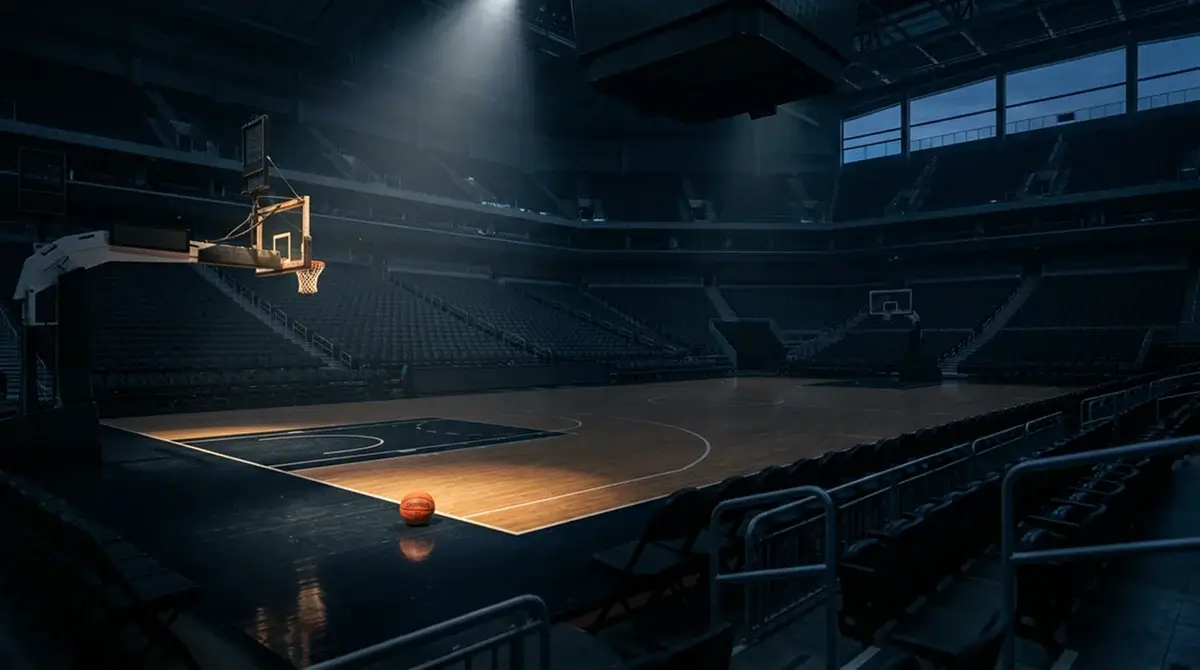 Empty NBA basketball court at twilight with rim and backboard visible under arena lighting
